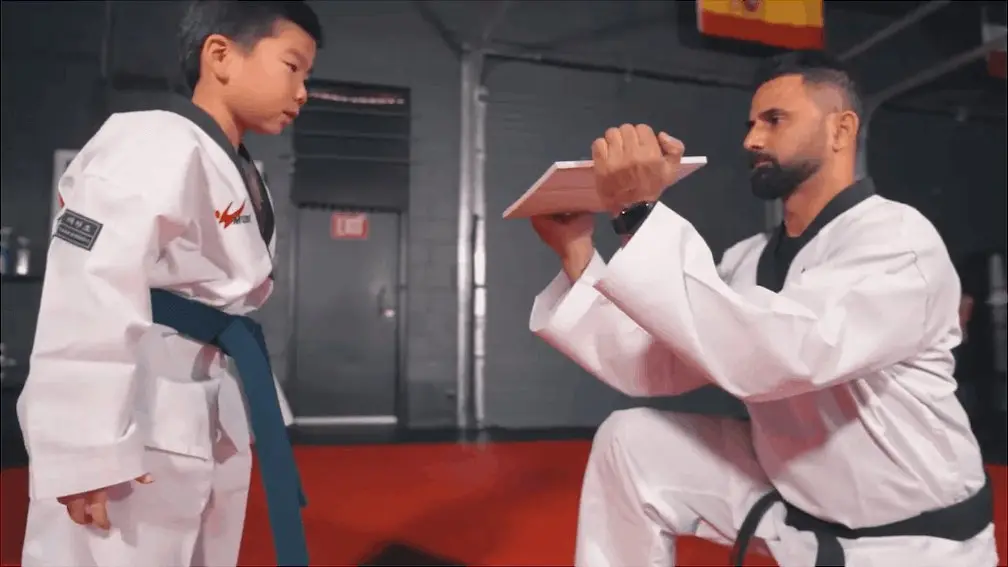 Master Shakeel Chaudhry holds a board for a young Dragon Taekwondo student