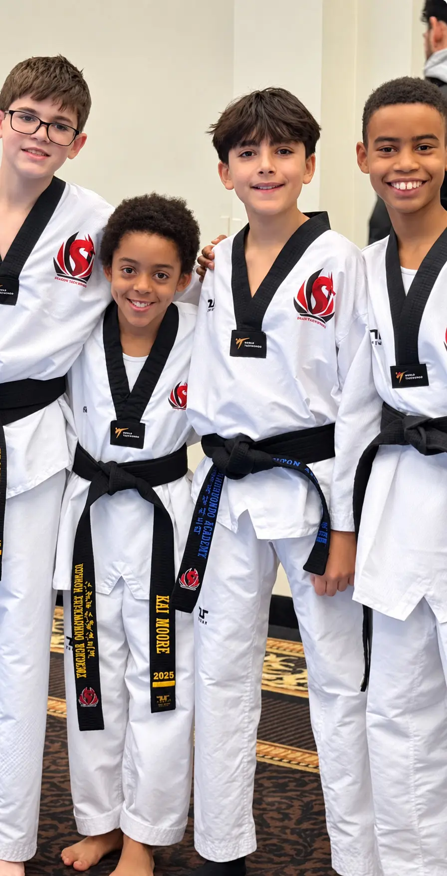 Four smiling Dragon Taekwondo students with their black belts