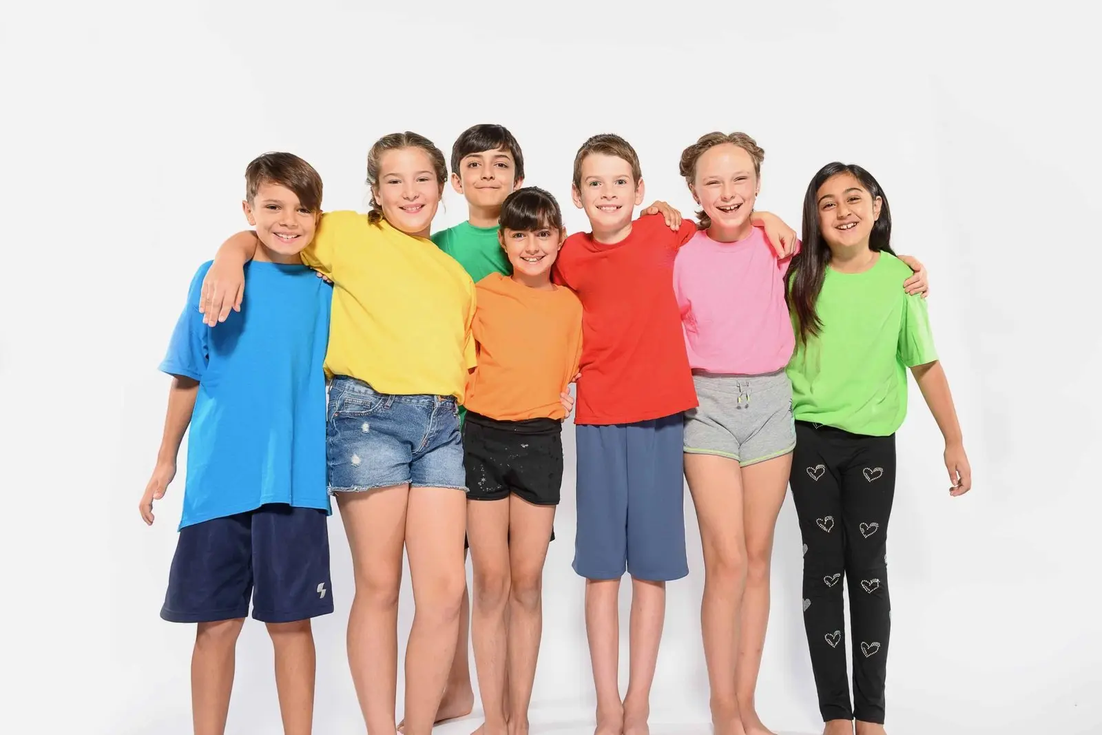 Seven children in colourful camp T-shirts, arm in arm and smiling