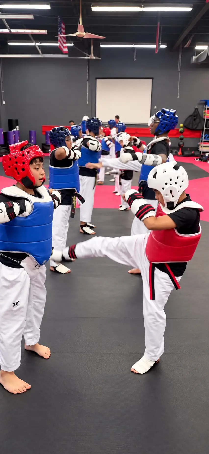 Young Dragon Taekwondo students in helmets and chest protectors practising kicks