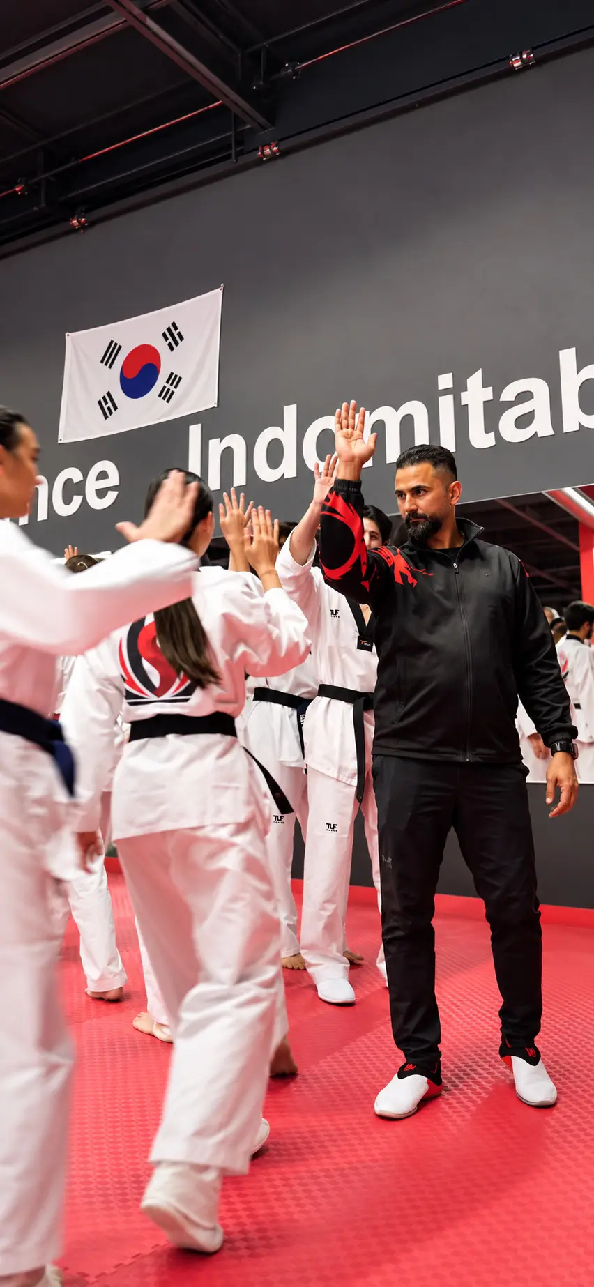A coach high-fives a line of Dragon Taekwondo students