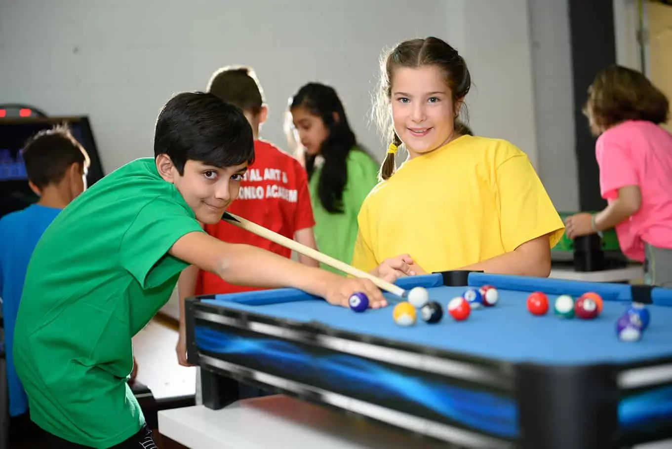 Kids in bright T-shirts playing pool