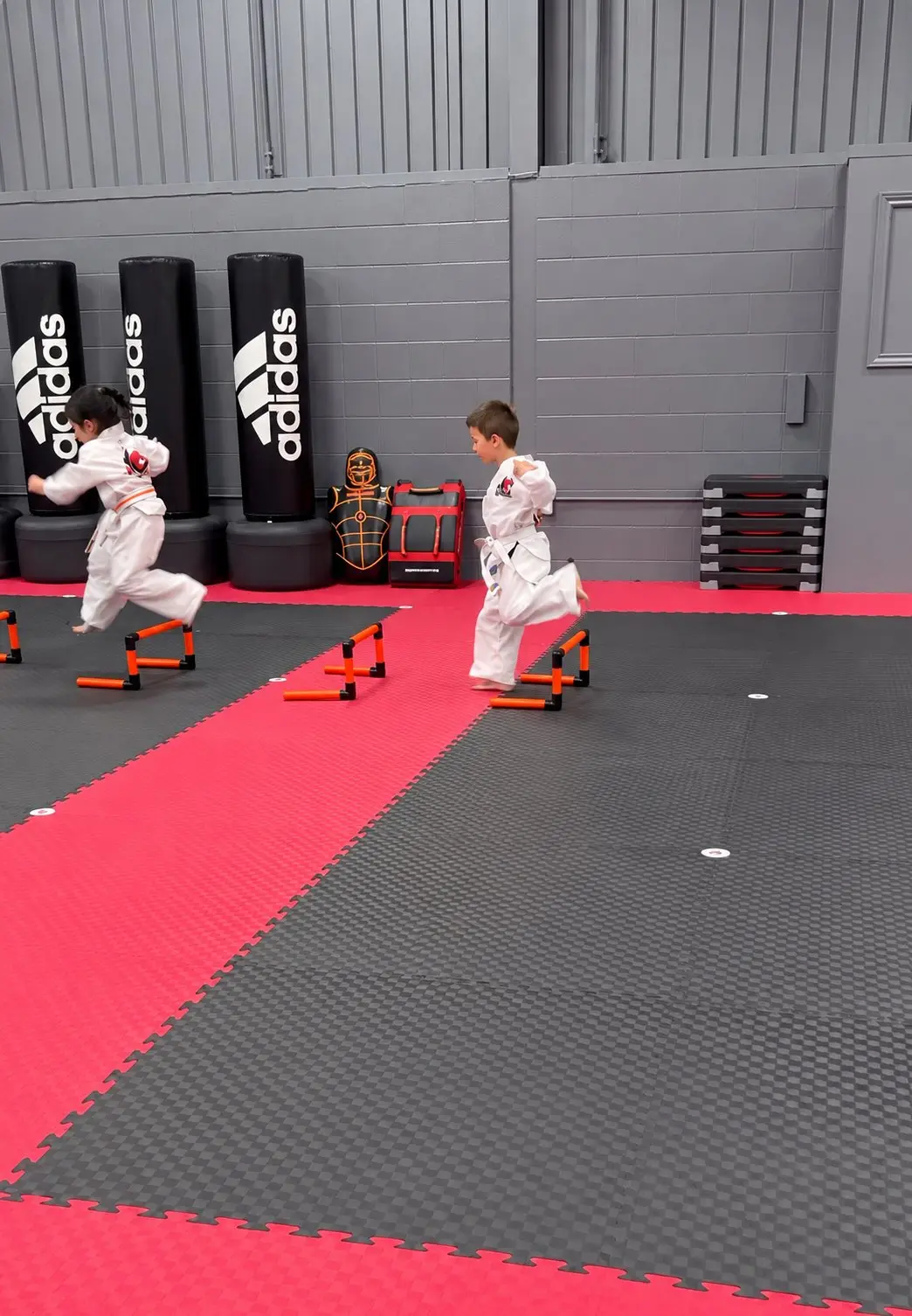 Young Dragon Taekwondo students jumping low hurdles in a drill