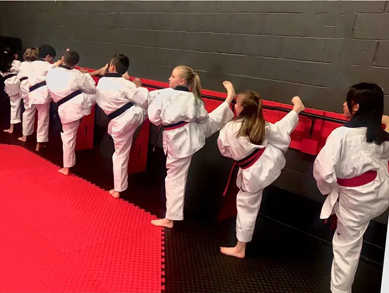 Students practise side kicks at the padded wall