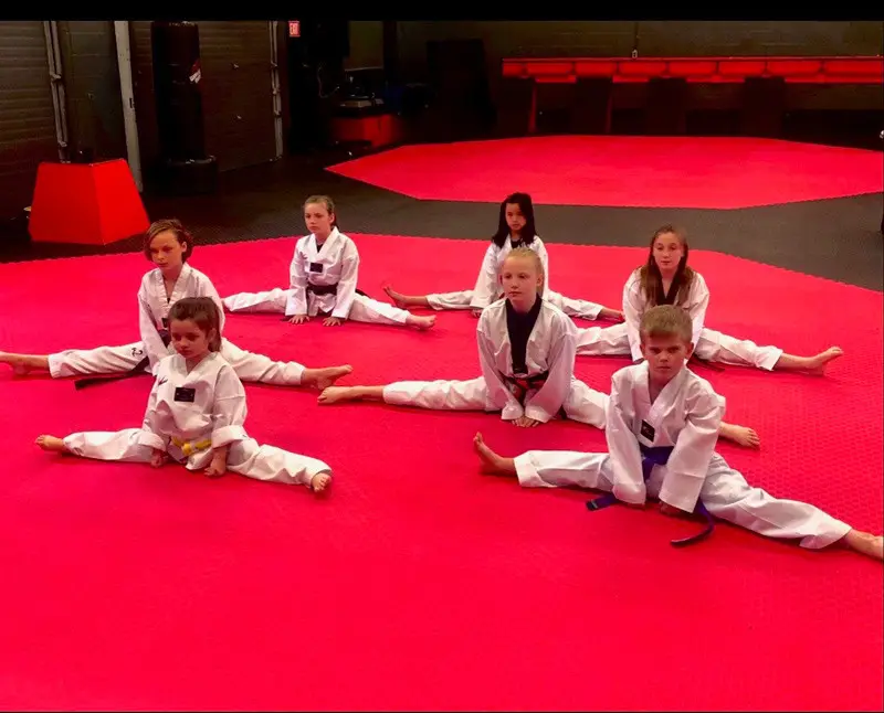 Students stretching into the splits on the mats