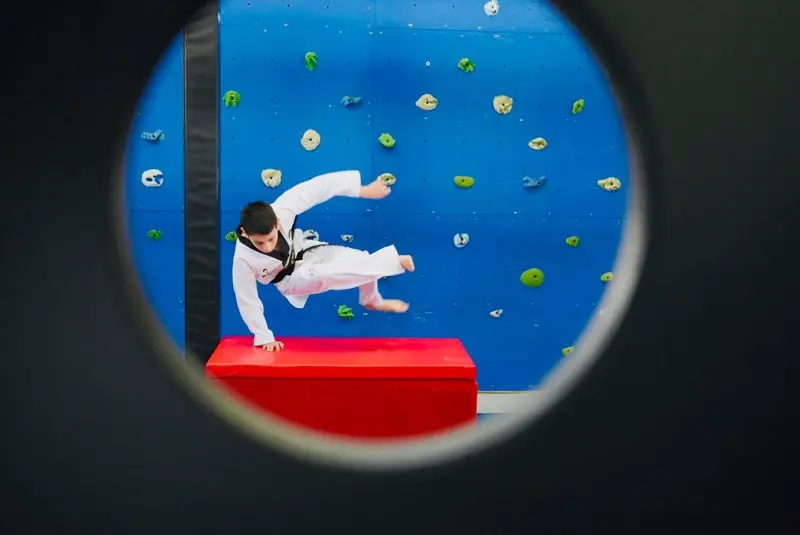 A Dragon Taekwondo student seen through a round window on the indoor ninja course