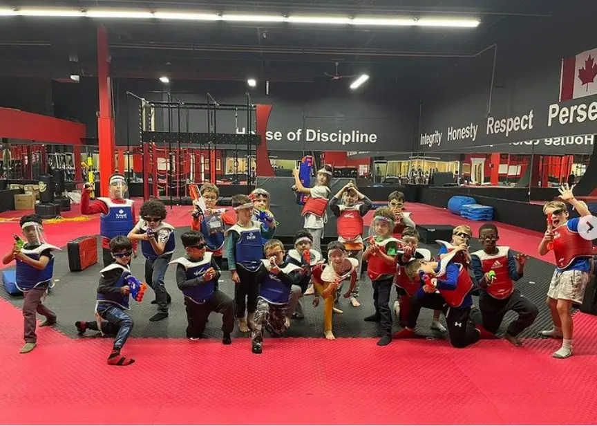 Kids in vests and goggles pose for a group photo on the mats