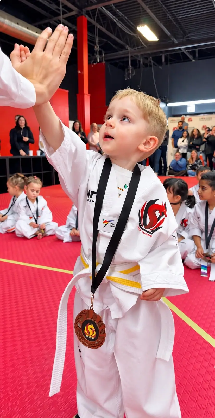 A Little Dragons student with a medal around his neck giving his instructor a high five