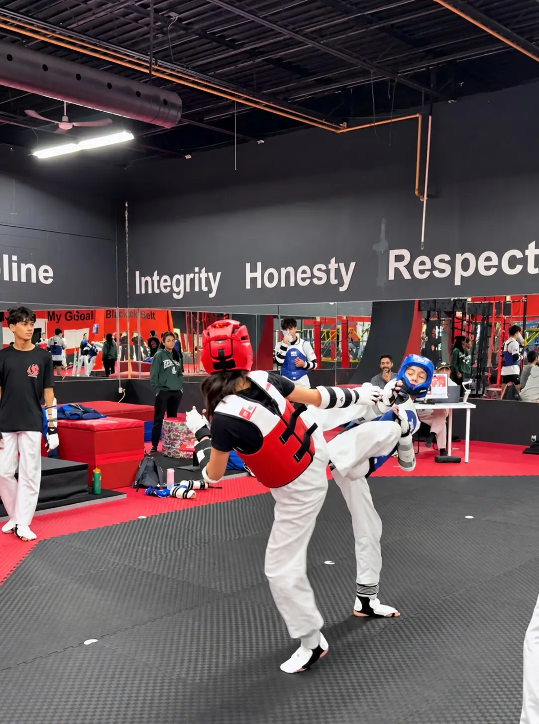 Two Dragon Taekwondo students sparring in helmets and chest protectors