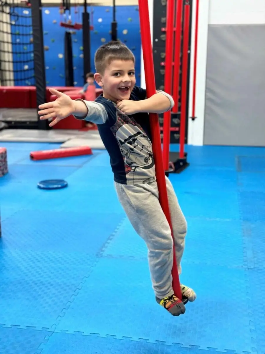 A child on the rope swing on the Dragon Taekwondo indoor ninja course
