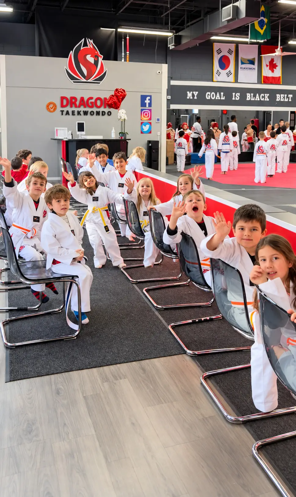 Young Dragon Taekwondo students in uniform waving from their seats