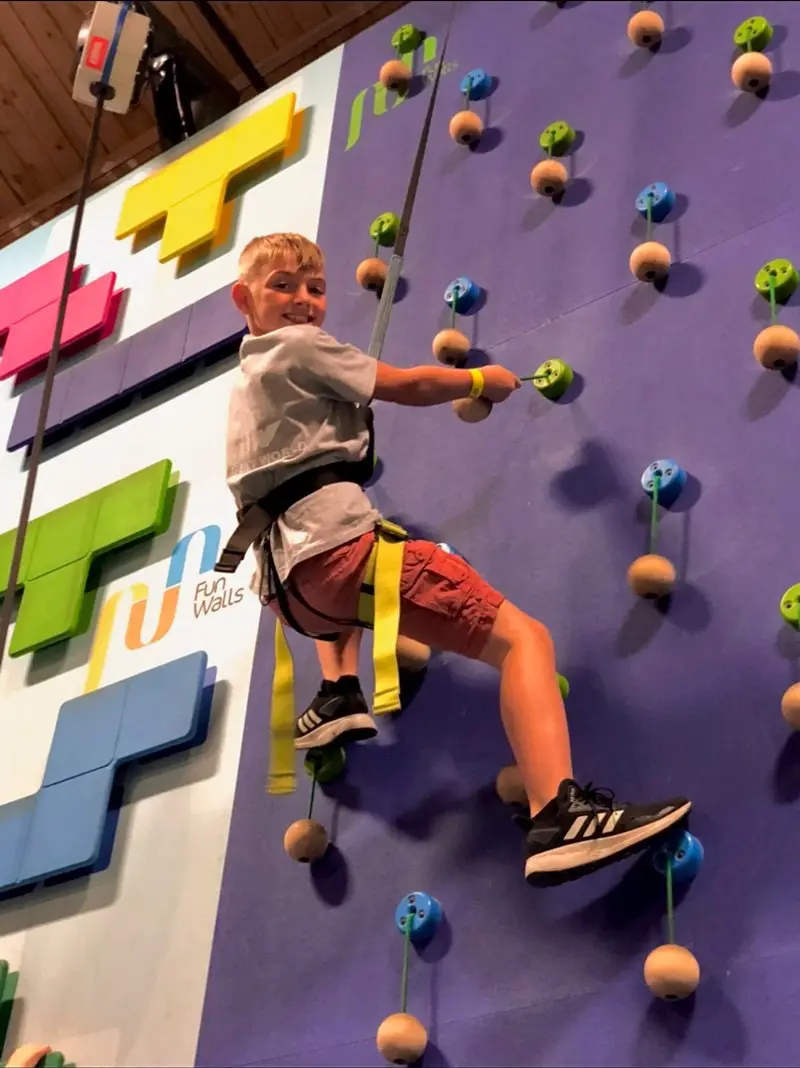A child on a climbing wall on a Dragon summer camp field trip