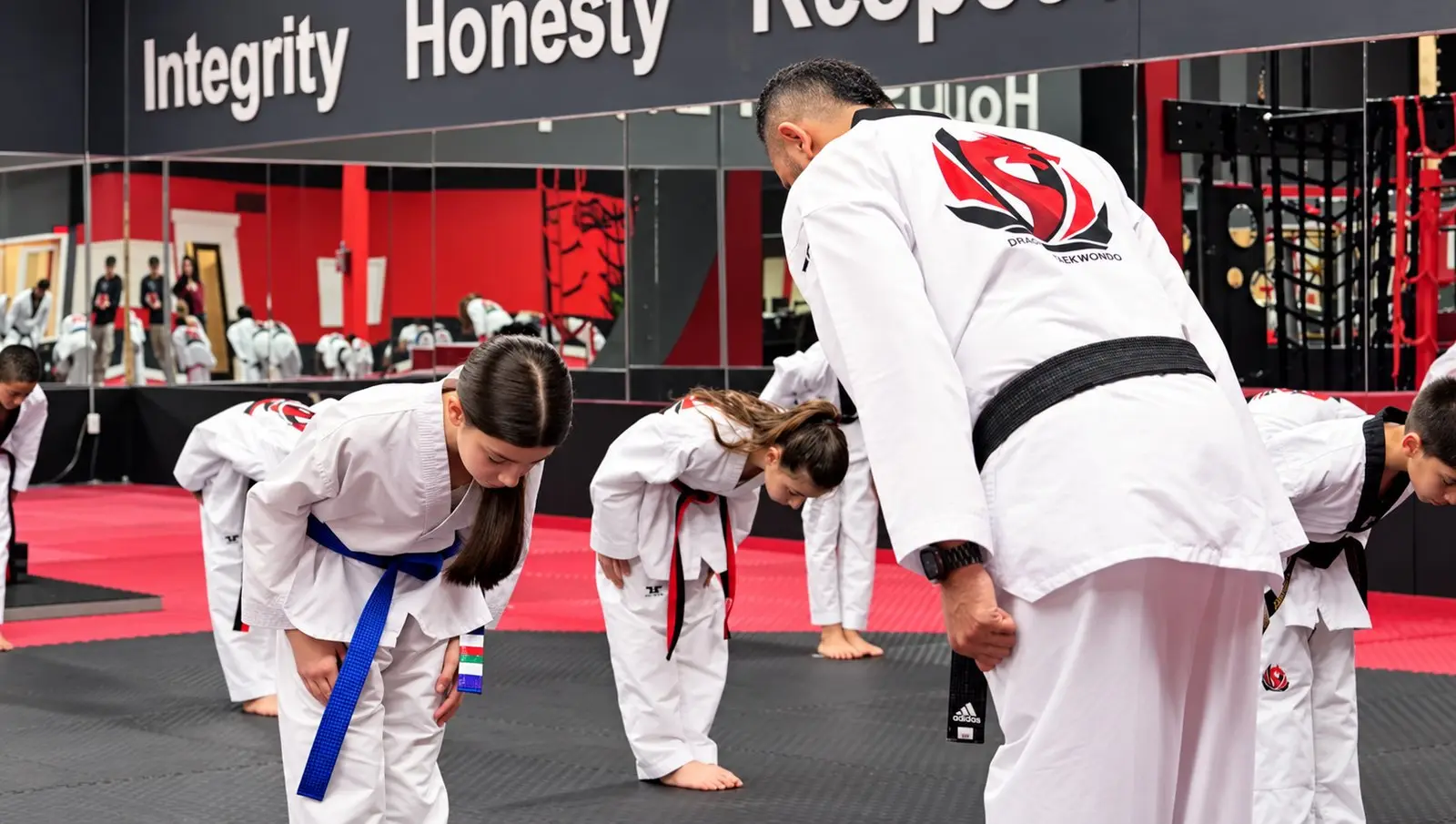 A Dragon Taekwondo black belt bowing with students in class