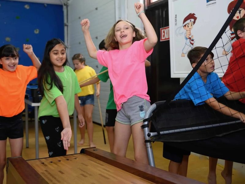 Kids in bright T-shirts cheering while they play games