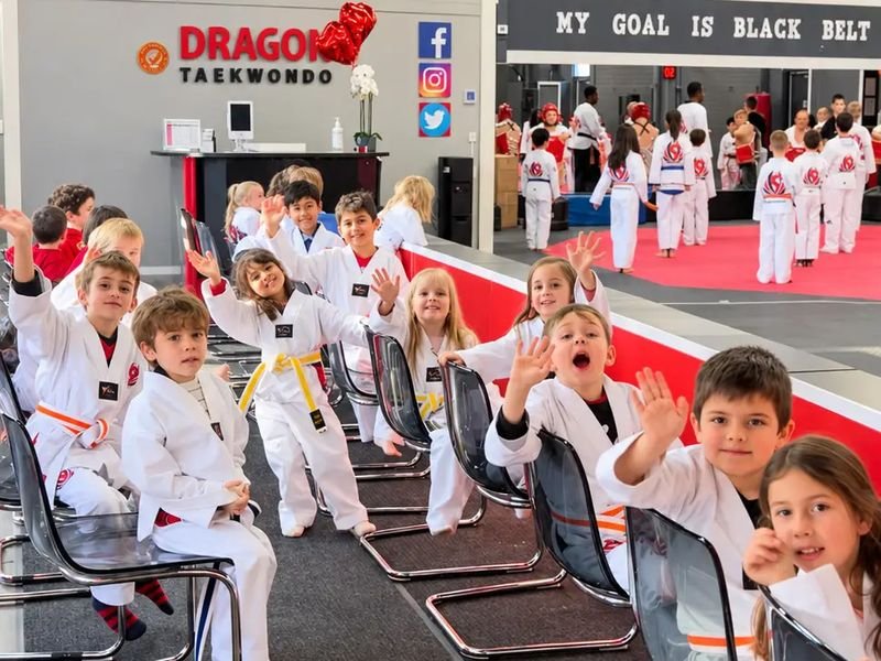 Young Dragon Taekwondo students in uniform waving from their seats