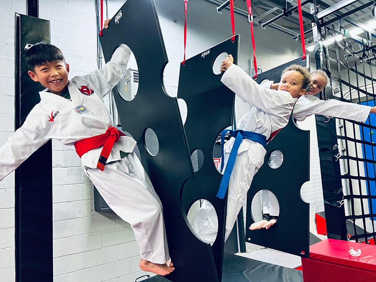 Students smiling as they climb through the holey wall on the ninja course