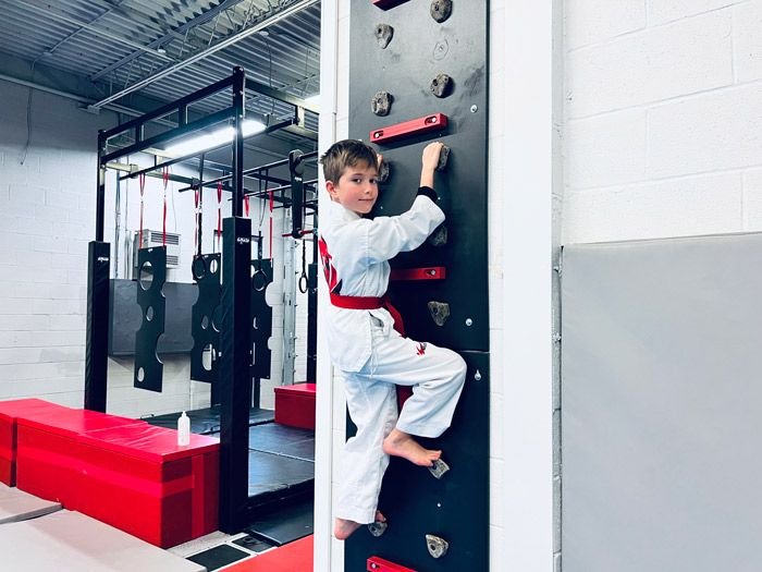 A student climbing a wall on the ninja course