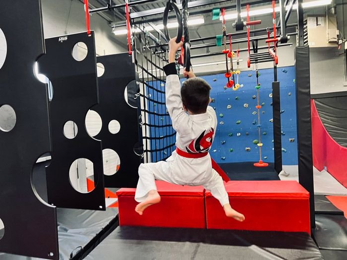 A student swinging on the rings on the ninja course
