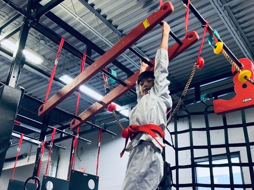 A student on the monkey bars on the ninja course