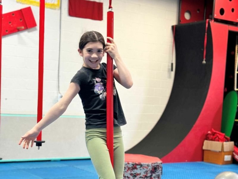 A girl swinging on a rope on the ninja course
