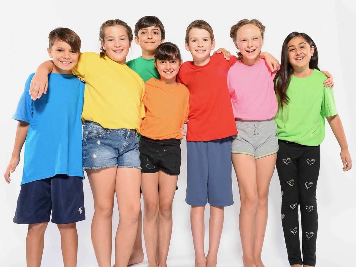 Seven smiling children in colourful T-shirts, arm in arm